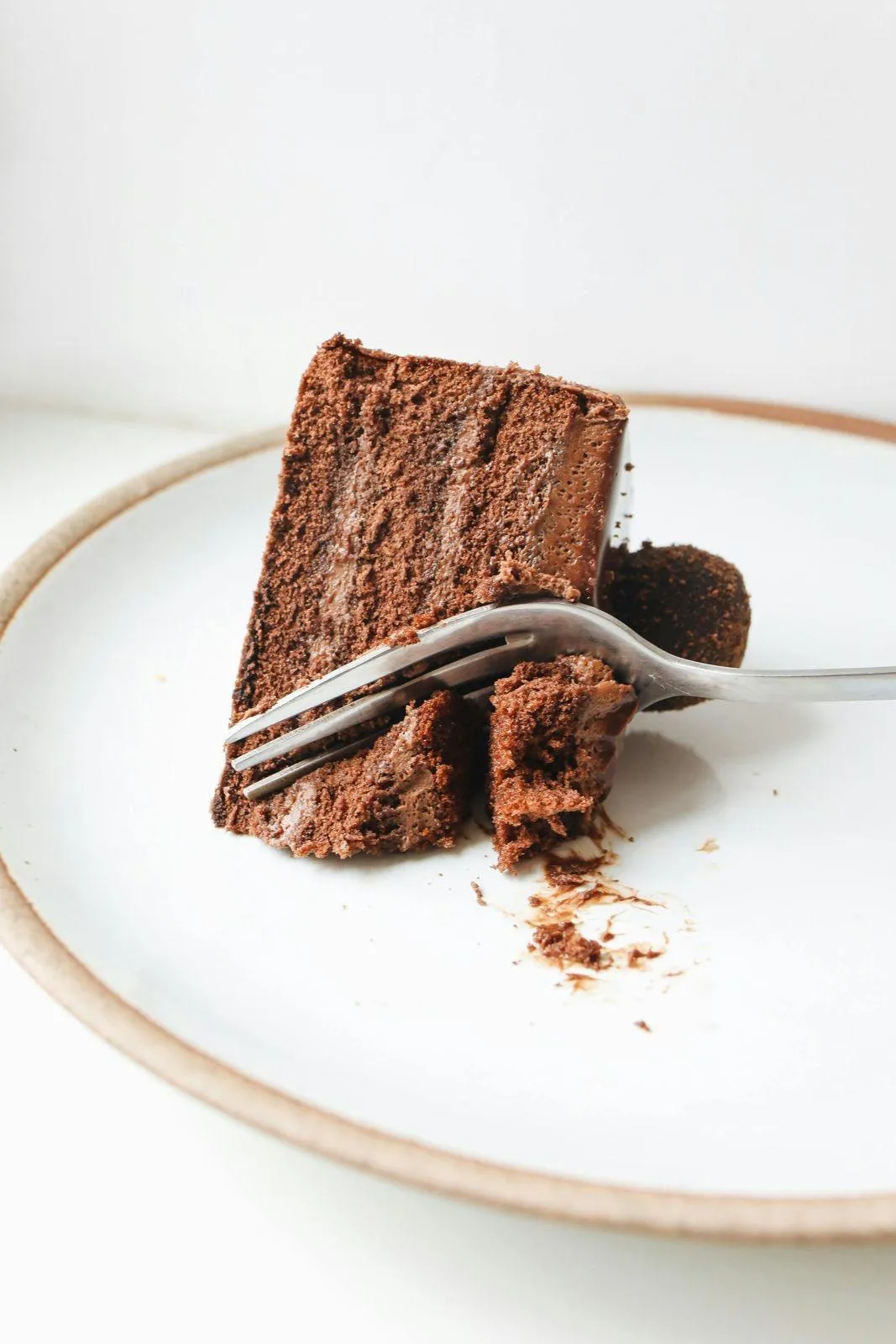 A slice of rich chocolate cake on a rustic plate