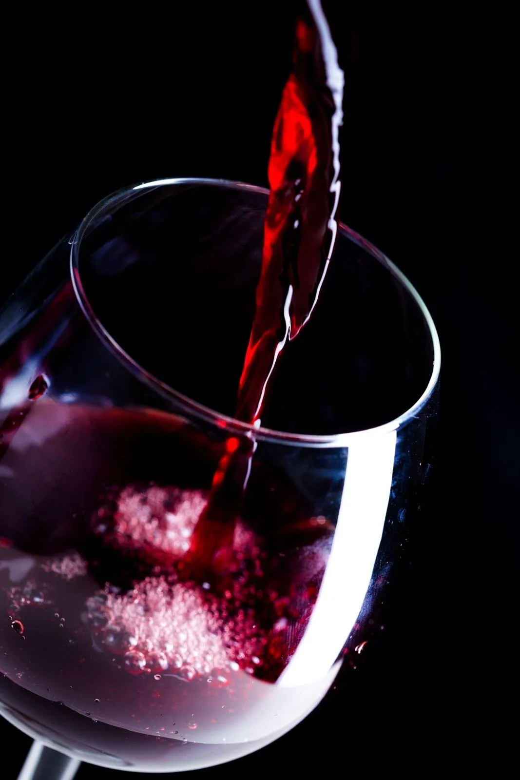 Red wine being poured into a glass against a dark background