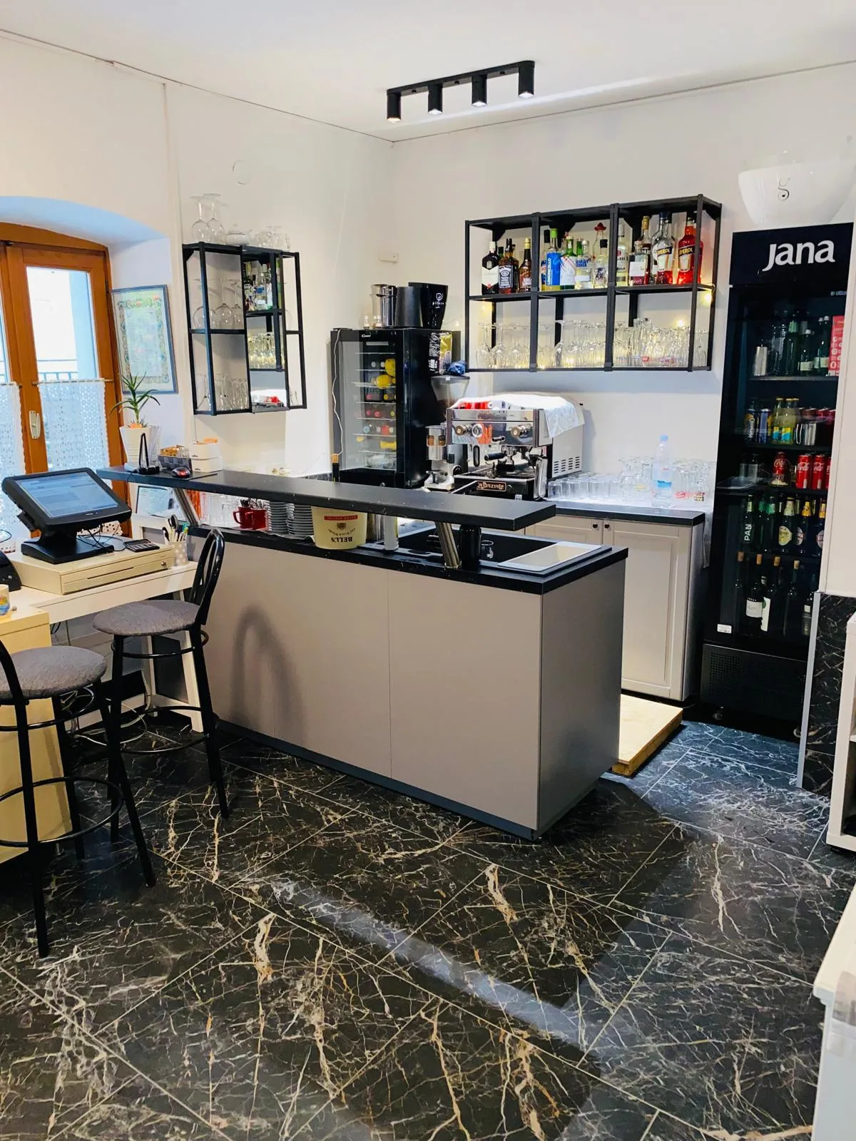 The interior bar counter with an espresso machine, glassware and spirits, on a polished black marble floor